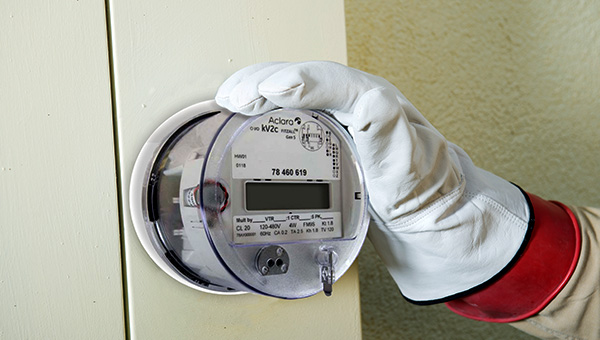 Advanced electric meter on a wall with hand holding it