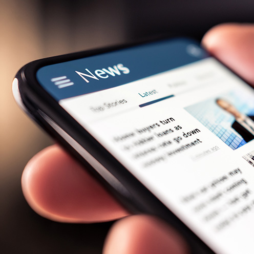 Person holding a mobile phone showing news headlines